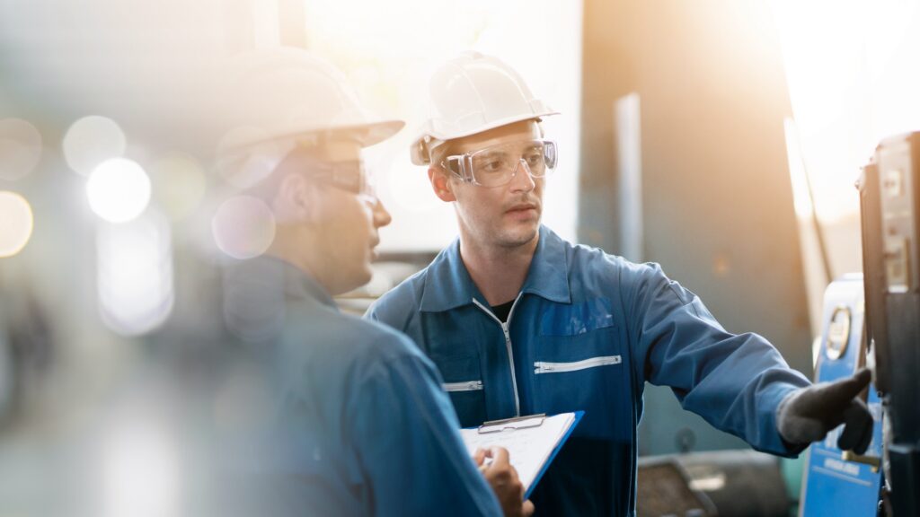 two people in hard hats and uniforms discussing over a clip board